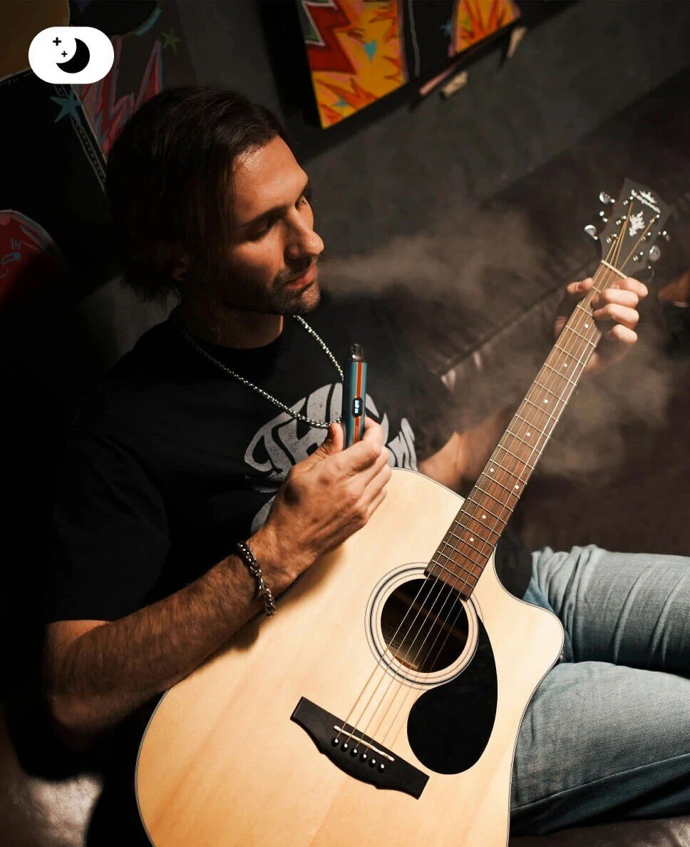 A man playing guitar and using the VAPORESSO VIBE in PWR Mode at night, representing its power for intense flavor and vapor production.